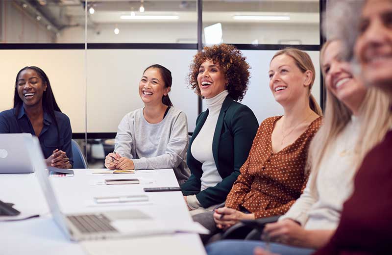 Women at board room table listening to speaker