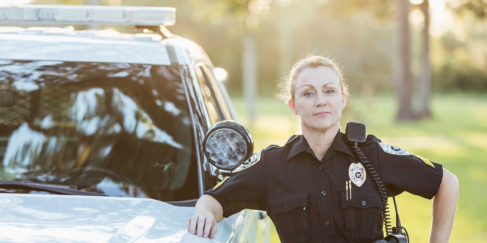 Female police officer leaned against car