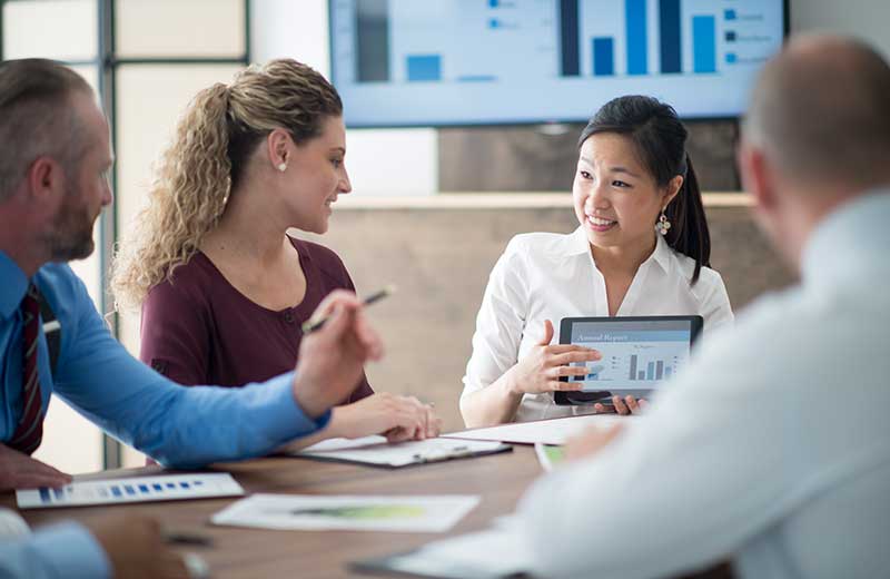 Business analytics certificate students around table with charts