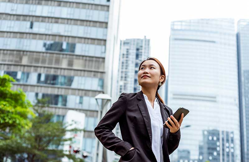 woman looking up at skyscraper in city