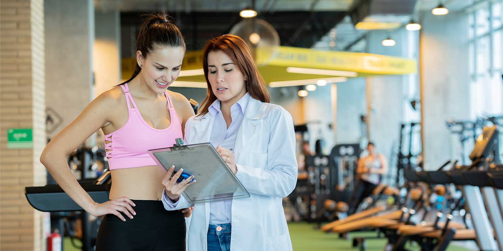 health and wellness professional talking with woman in gym