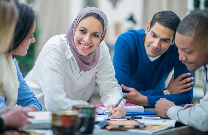 student in hijab at table with classmates