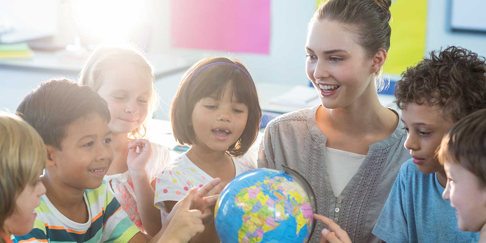 Teacher with group of students looking at a globe